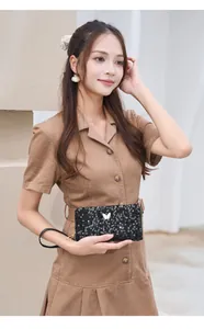 Dettaglio della pochette nera con paillettes e farfalla dorata tenuta da una donna in abito