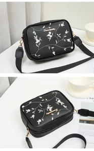 Detail of floral embroidery and gold metal logo on the black crossbody camera bag