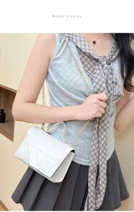 Detailed view of white quilted crossbody bag with gold chain strap and metal bar detail