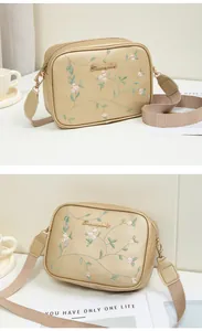 Detail of floral embroidery on light gold lychee grain faux leather crossbody bag