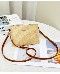 Dettaglio borsa a tracolla in paglia intrecciata con finiture dorate e cinturino in pelle