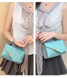 Close-up of mint green quilted crossbody bag with gold chain and V-shaped flap detail
