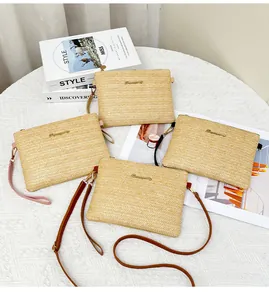 Dettaglio di pochette in paglia intrecciata con tracolle in pelle e logo dorato
