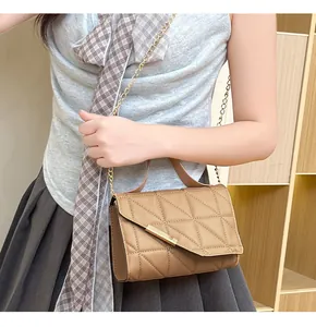 Detail of khaki quilted crossbody bag featuring gold buckle and chain shoulder strap