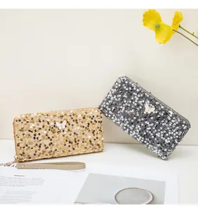 Dettaglio di pochette lunghe con paillettes oro e argento e accento a farfalla