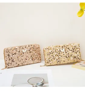 Dettaglio di pochette glitterate in oro rosa e oro con decorazioni a farfalla e zip