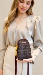 Macro view of dark brown leather crossbody phone bag with gold zipper and logo plaque