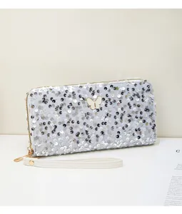 Dettaglio della pochette di paillettes argento con chiusura a farfalla e cinturino