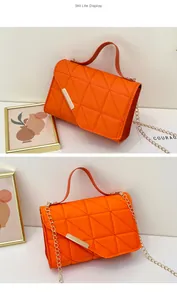 Detailed view of orange quilted PU leather texture with gold metal lock and chain strap