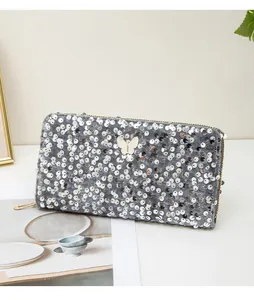 Dettaglio della pochette lunga in velluto grigio con paillettes e decoro a farfalla