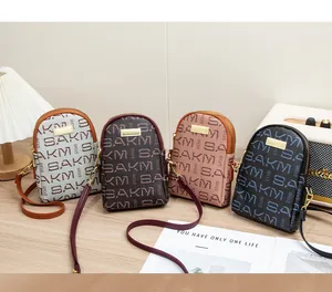 Multiple colors of letter-print crossbody phone bags arranged on a textured wooden table
