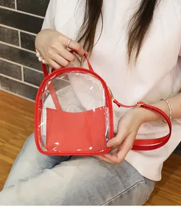 Dettaglio di un mini zaino in PVC trasparente con finiture rosse indossato da una modella