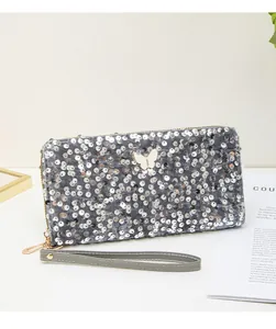 Dettaglio della trama di paillettes grigie con ornamento a farfalla bianca sulla pochette