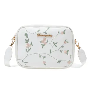 White crossbody camera bag with floral embroidery and wide shoulder strap