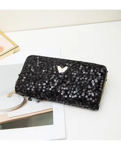 Dettaglio pochette lunga con paillettes nere, fibbia a farfalla dorata e zip in metallo