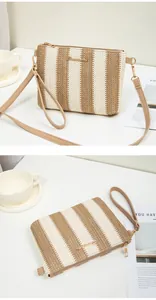 Detail of hand-woven striped crossbody bag with gold metal zipper and leather strap
