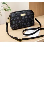 Detailed shot of dual gold zippers and SAKM letter print on the black crossbody phone bag
