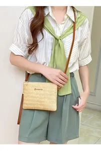Dettaglio borsa a tracolla in paglia intrecciata beige con cinturino in pelle marrone