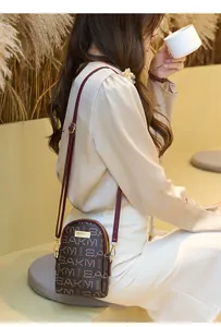 Detailed view of a brown patterned crossbody phone bag with adjustable shoulder strap