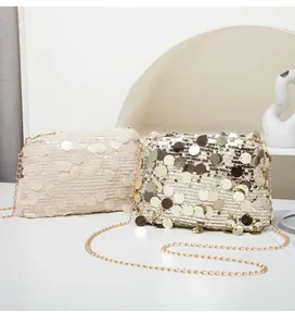 Close-up of stylish glitter crossbody bags in cream and gold with metallic paillettes