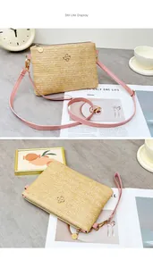 Détail du tissage en paille avec logo trèfle doré et bandoulière rose sur le sac à bandoulière