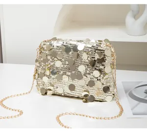 Close-up of golden sequins on small crossbody bag with metallic chain strap and shimmer