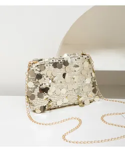Close-up of golden sequins and metallic chain on a sparkling small square crossbody bag