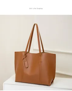 Detail view of large brown soft leather tote bag with tag ornament and neat stitching