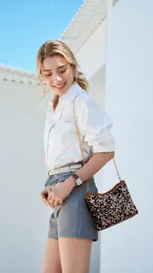 Detail view of a brown sequin bucket bag with a luxury gold chain strap on a model