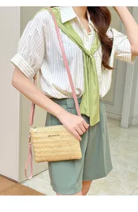 Dettaglio borsa a tracolla in paglia beige con cinturino rosa e logo dorato