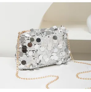 Detail of silver sequined crossbody bag with metallic finish and gold chain strap