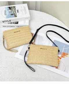 Dettaglio di pochette in paglia intrecciata a spina di pesce con cinturini in pelle e metallo