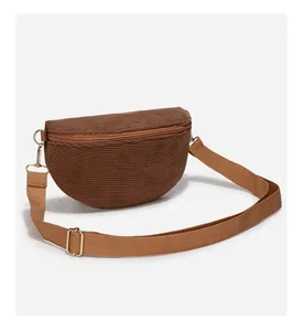 Close-up of brown corduroy crossbody bag texture with golden zipper and metal hooks
