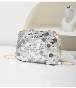 Detail of silver sequin texture and gold chain strap on a shimmering party clutch bag