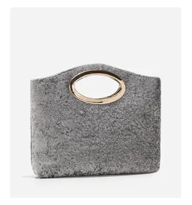 Close-up of grey felt handbag with an oval gold metal handle and textured fabric