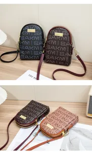 Detail of dual zipper small crossbody bag featuring SAKM letter print and metal logo