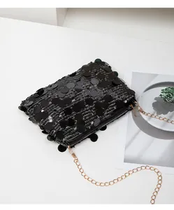 Detailed close-up of shiny black sequin texture and gold metal chain on small crossbody bag