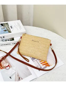 Dettaglio della borsa a tracolla in paglia intrecciata con cinturino marrone e logo
