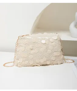 Detailed view of large white sequins and gold chain strap on a shimmering crossbody bag
