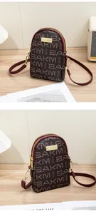 Detail of the dual-zipper crossbody phone bag in dark red with SAKM logo print