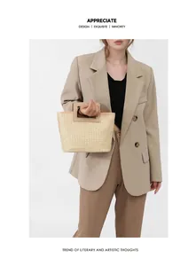 Detail of woven straw handbag featuring a rectangular handle and oatmeal texture