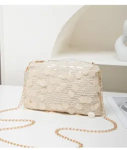 Detailed view of beige sequined small square bag with elegant golden chain strap
