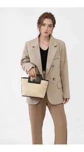Detail of hand-woven straw tote bag featuring contrast black leather trim and handles