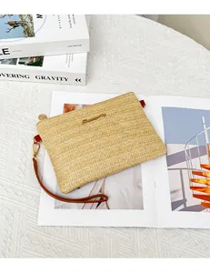 Dettaglio della pochette in paglia intrecciata con trama a V e cerniera dorata