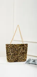 Detail of shimmering gold and black sequins on a chic chain shoulder tote bag