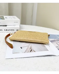 Dettaglio pochette in paglia intrecciata con cinturino in pelle su una rivista