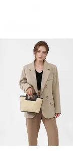 Detail view of woven straw handbag with black leather trim held by a fashion model
