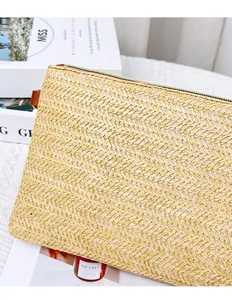 Dettaglio della pochette in paglia intrecciata con motivo a spina di pesce e zip in metallo