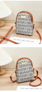 Detailed view of dual-zipper compartments and metallic SAKM plaque on monogram phone bag