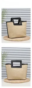 Detail of the woven straw tote bag with black faux leather handles and square cutout design